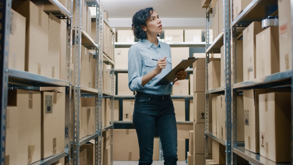 Person looking through their UtraStor storage locker, lined with boxes. They are carrying a clip board of storage items.