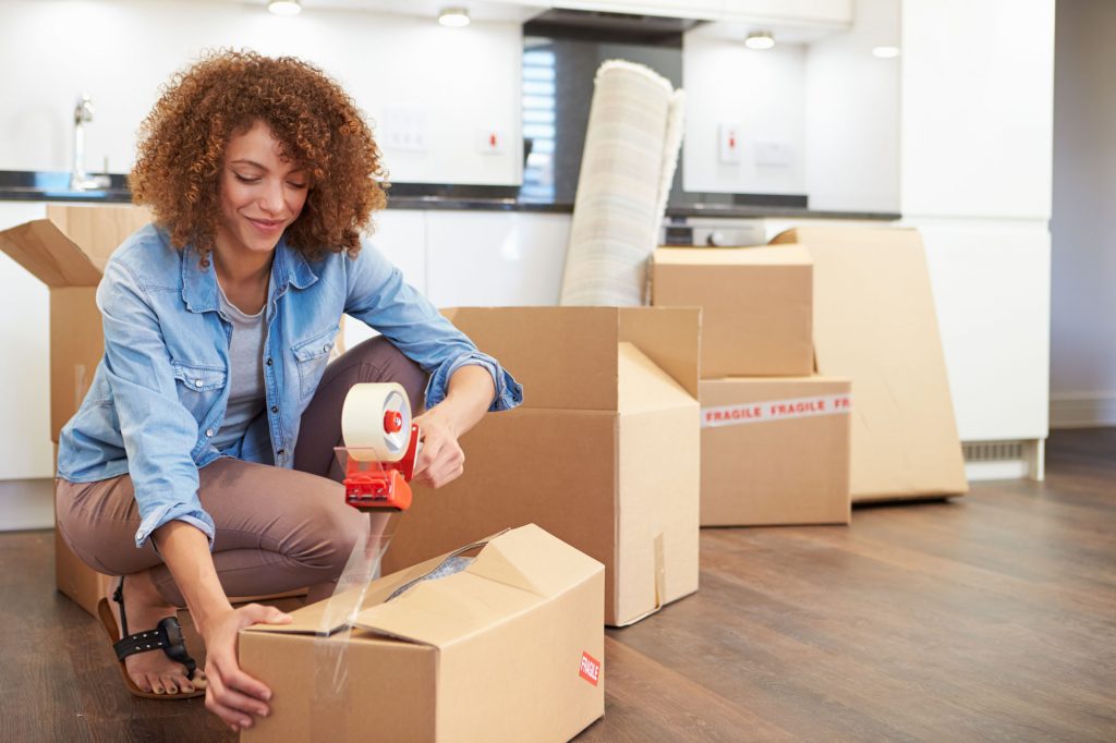 Person taping up a storage box, with move moving boxes behind them to move into UltraStor.