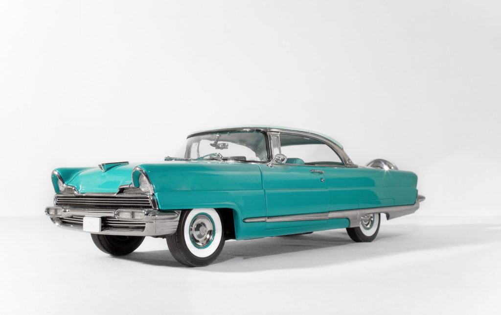 A blue classic car against a white backdrop.