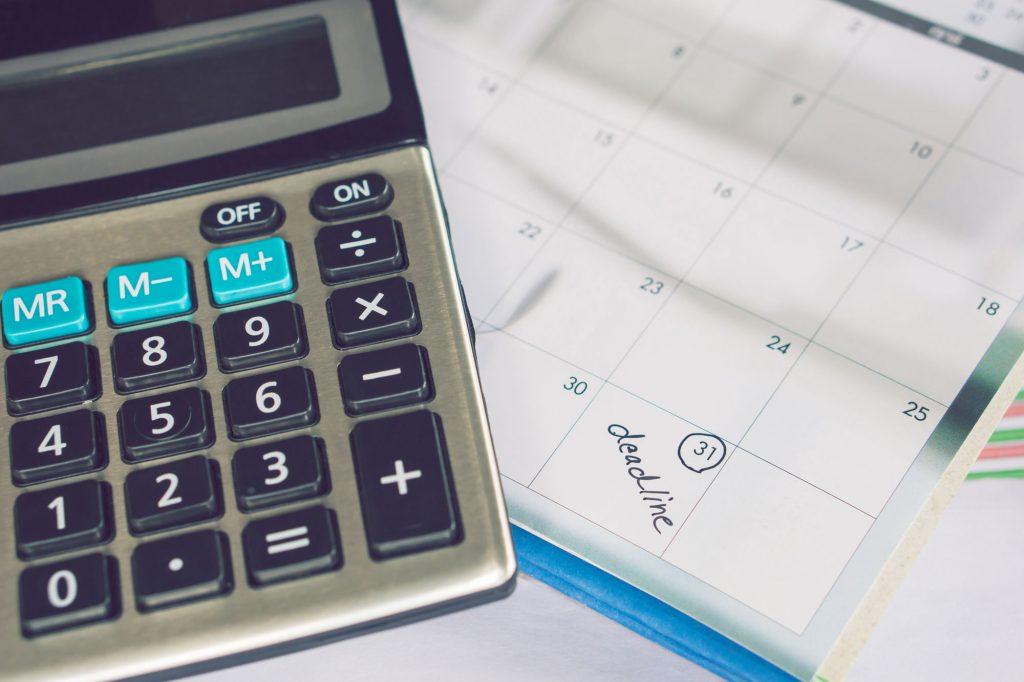 Calculator with a calendar in the background.